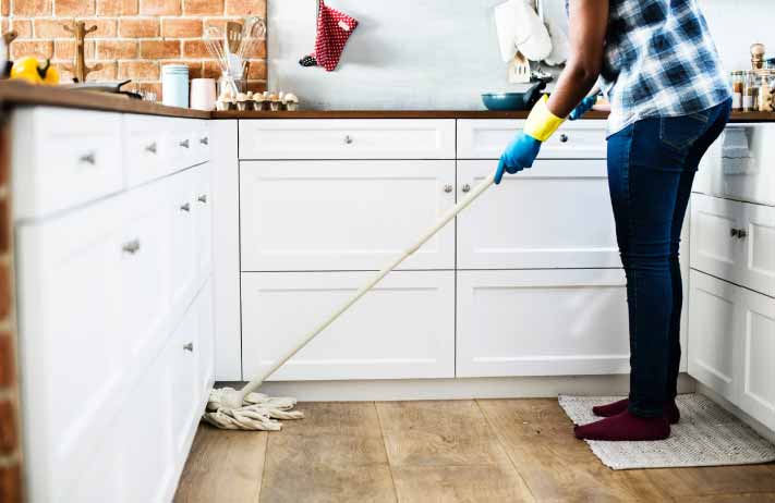 Women moping timber floor in kitchen wearing gloves