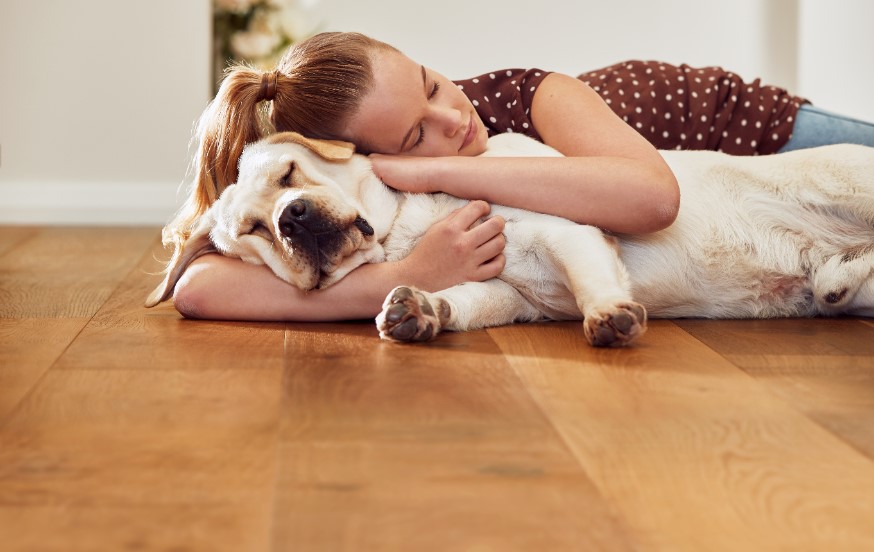 Girl laying on timber floor with dog