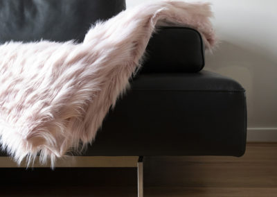 Modern leather sofa with pink throw blanket on timber flooring perth
