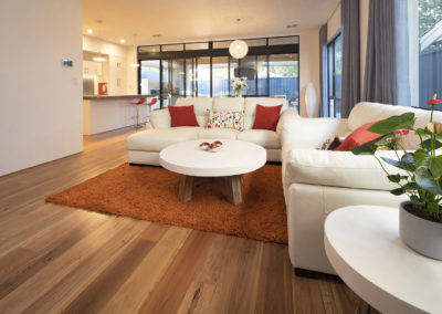 White sofa set on orange rug with Blackbutt timber flooring