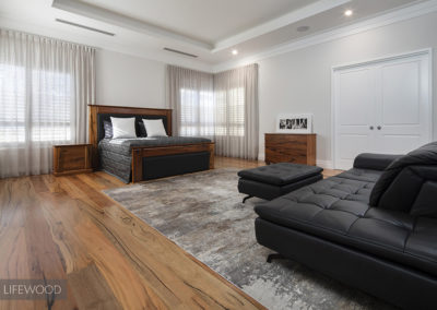 master bedroom with black leather sofa and marri flooring